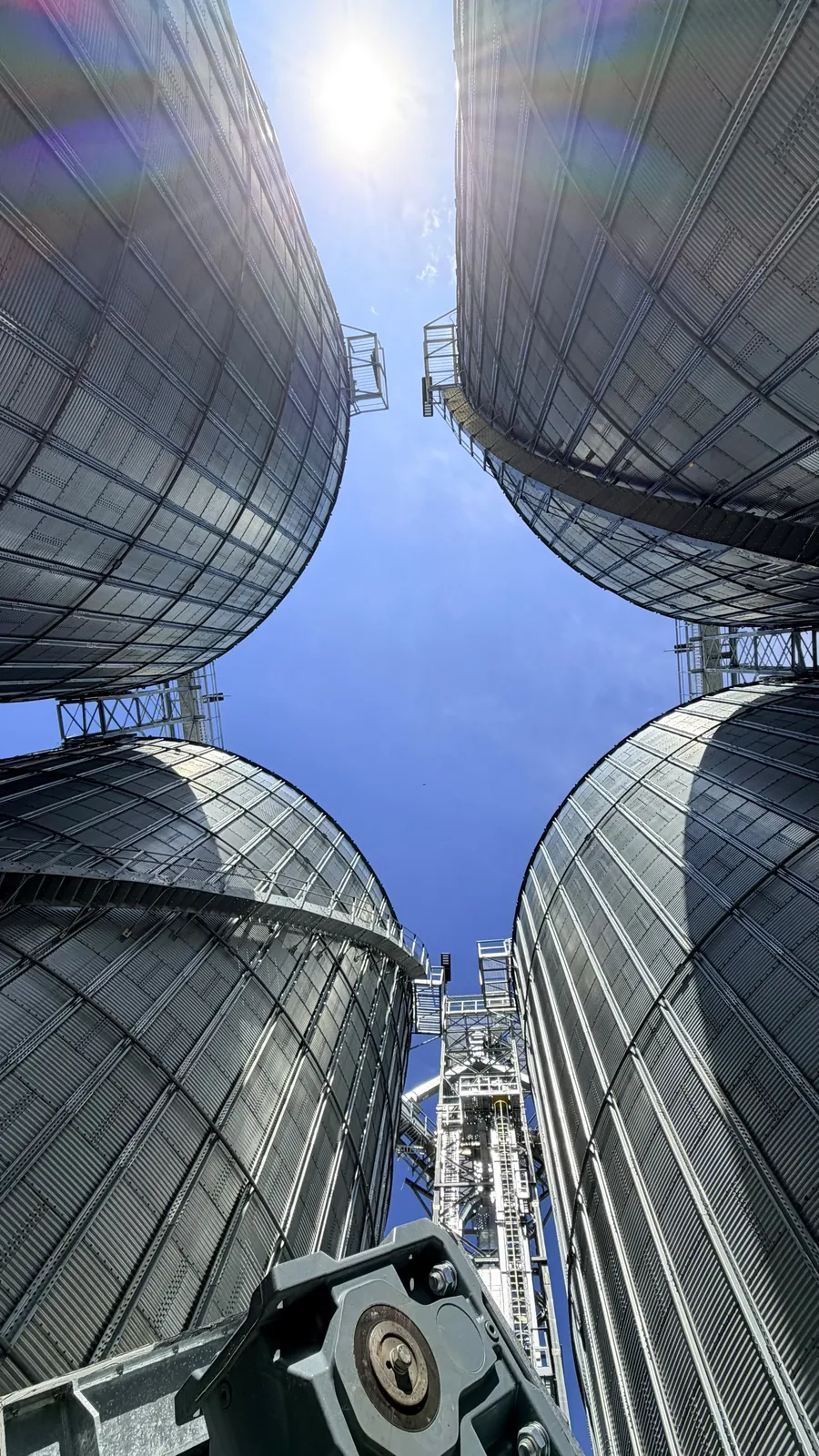 Vista hacia el cielo entre cuatro silos de granos